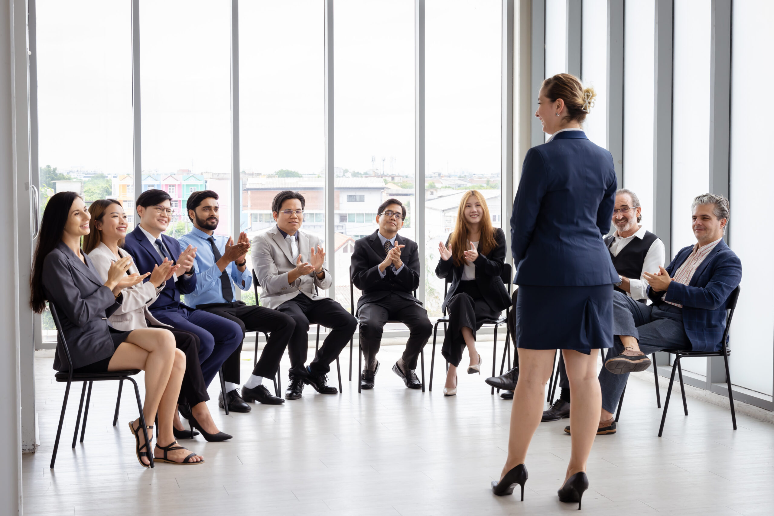 Team applauds a presenter leading a leadership training for managers in the office.